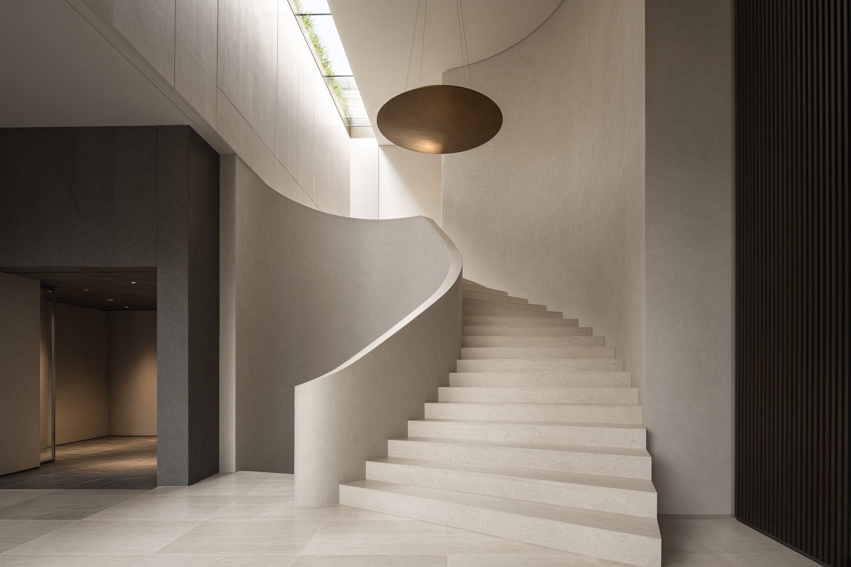 A monumental stone stair in a double-height interior, a figure descending.
